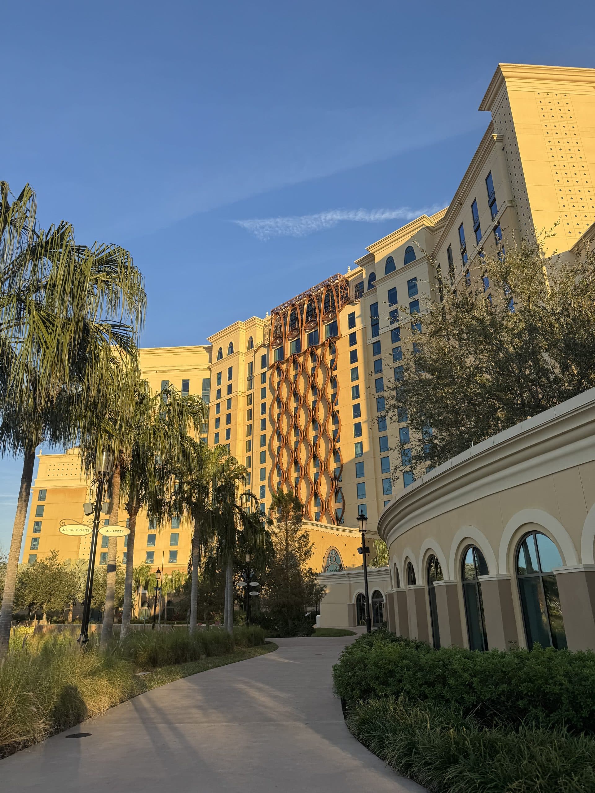 Gran Destino Tower with palm trees lining the walkway and the sun shining on the building